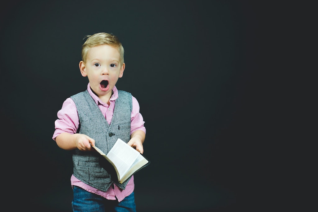 Boy showing surprise holding book