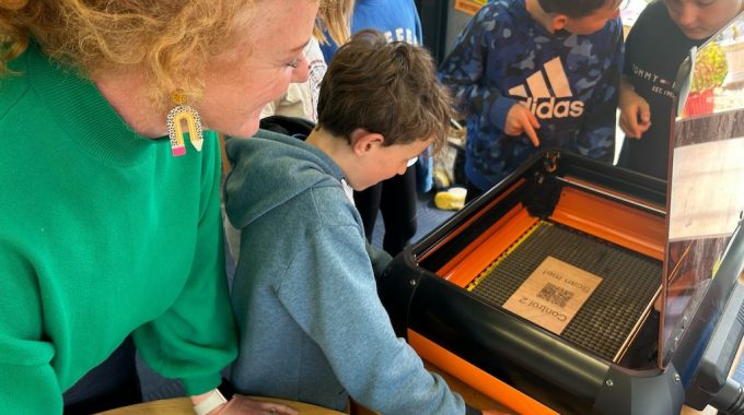 Three Boys And A Woman Looking At A QR Code On A 3D Printer