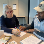 Woman and man sitting at desk writing with pens