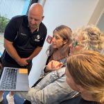 Man and three women looking at laptop having discussion