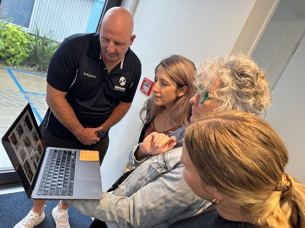 Man and three women looking at laptop having discussion